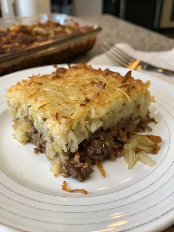 hamburger hashbrown casserole plated with a fresh green salad on the side