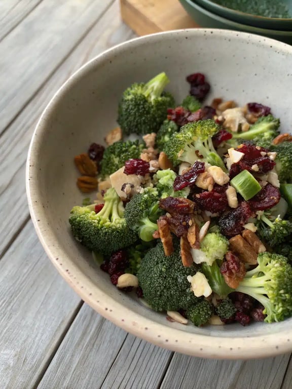 broccoli salad recipe beautifully plated on a picnic table with other dishes