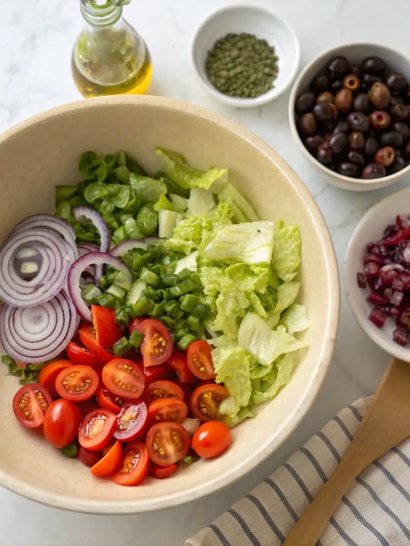 Step 4 for olive garden salad recipe — sprinkling cheese and croutons over greens