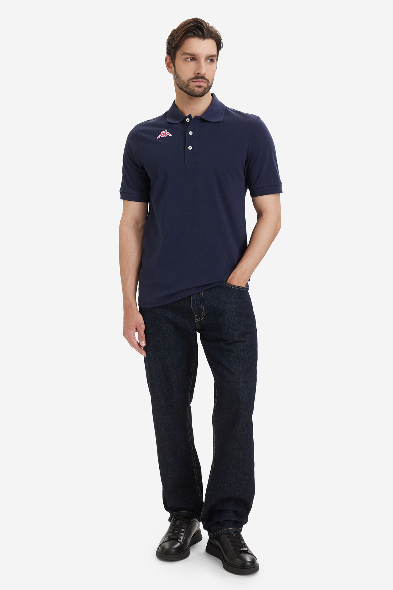 Model w koszulce polo i spodniach, sylwetka widoczna w całości.