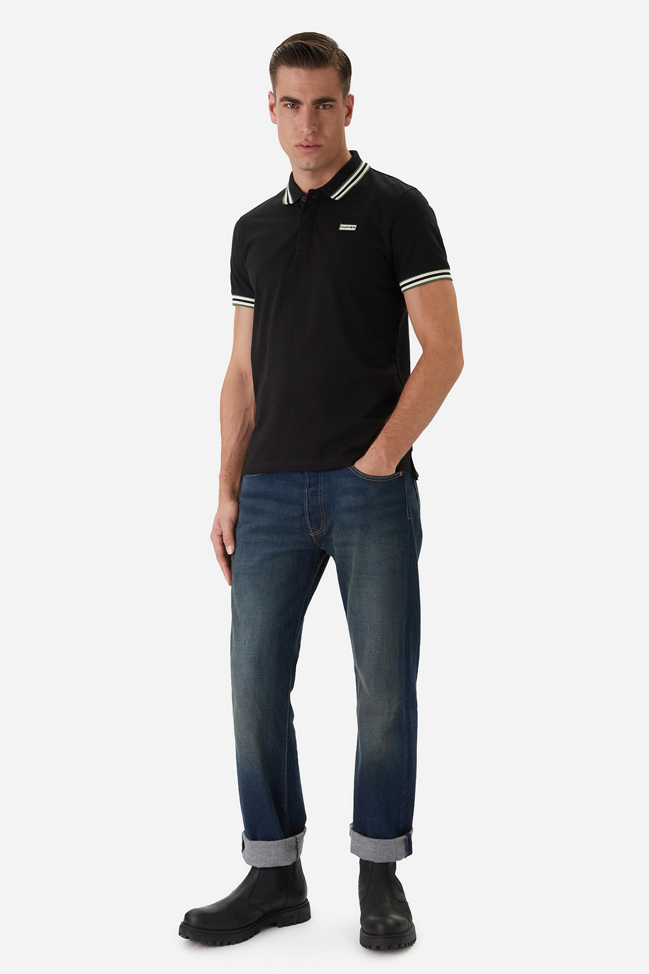 Model w koszulce polo i spodniach, ujęcie całej sylwetki pod lekkim kątem.
