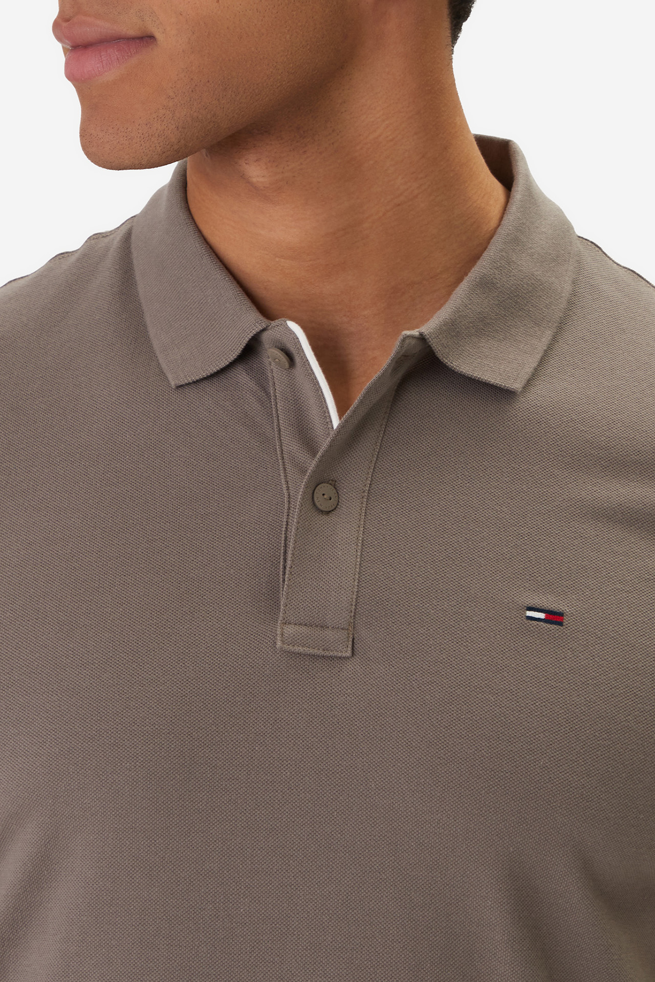 Zbliżenie na górną część koszulki polo na modelu.