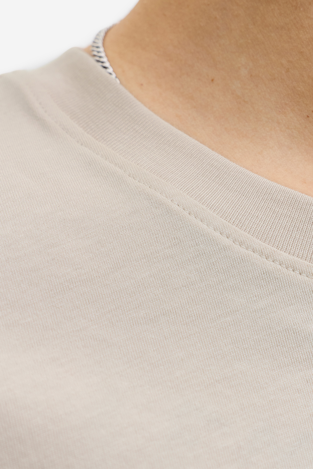 Zbliżenie na dekolt T-shirta, widoczny fragment szyi modela.