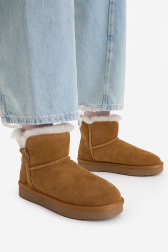Modelka w podwiniętych spodniach prezentuje krótkie buty na stopach.