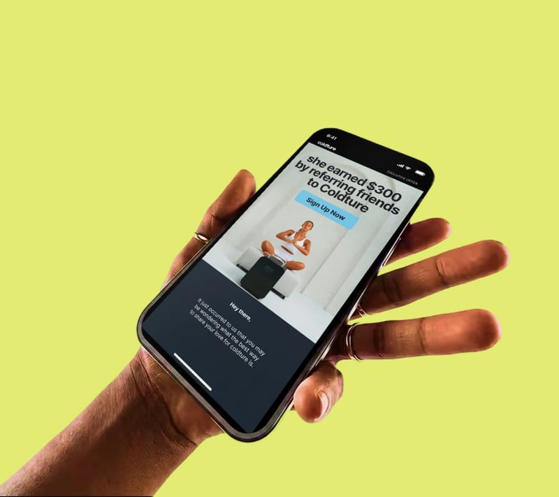 Coldture referral email on a phone held against a yellow background