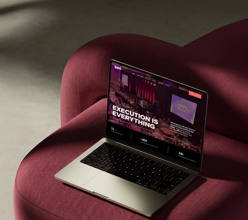 Savi website on a laptop resting on a burgundy armchair