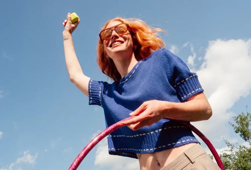 UGC creator laughing with a hula hoop against a blue sky