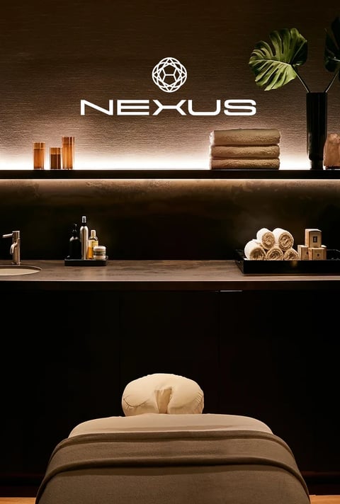 Nexus spa treatment room with warm lighting and rolled towels