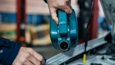 Automechanik v servisu dolévá do motoru čerstvý motorový olej, což je důležitý krok pro údržbu a dlouhou životnost vozidla.