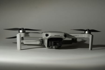 Bílý dron s rotory ve složené pozici, s kamerou umístěnou vpředu. Design dronu odkazuje na letectví a ilustruje, jak se 3D tisk využívá pro výrobu lehkých a přesných dílů pro drony a letecké modely.