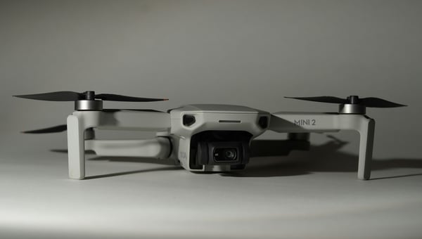 Bílý dron s rotory ve složené pozici, s kamerou umístěnou vpředu. Design dronu odkazuje na letectví a ilustruje, jak se 3D tisk využívá pro výrobu lehkých a přesných dílů pro drony a letecké modely.
