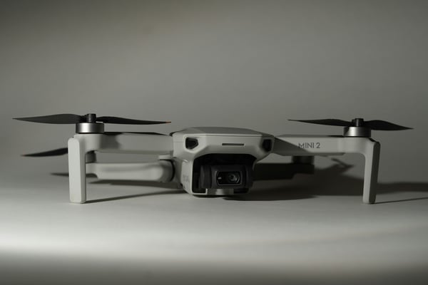 Bílý dron s rotory ve složené pozici, s kamerou umístěnou vpředu. Design dronu odkazuje na letectví a ilustruje, jak se 3D tisk využívá pro výrobu lehkých a přesných dílů pro drony a letecké modely.