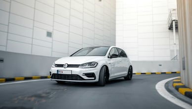 Volkswagen Golf R Mk7 facelift v pohybu na rampě moderního parkovacího domu s černými koly a panoramatickou střechou.