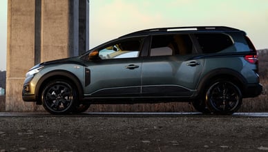 Šedá Dacia Jogger zaparkovaná z boku, sedmimístné rodinné kombi na moderní platformě CMF-B.