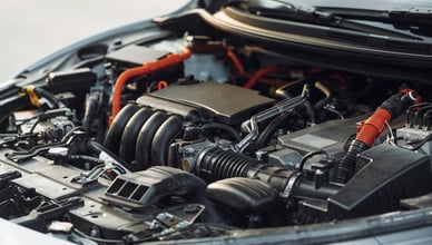 Моторный отсек современного автомобиля с открытым капотом и видимыми компонентами двигателя.