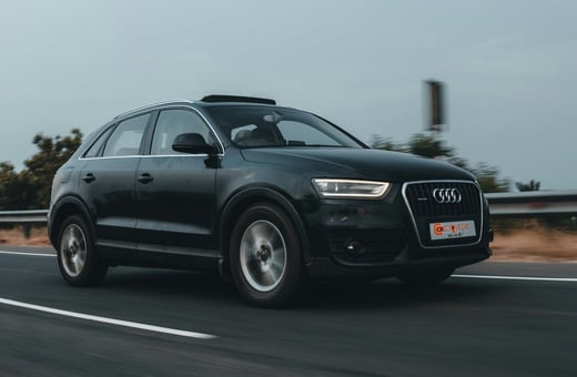 Чёрный роскошный внедорожник Audi Q3 в движении, символизирующий высокие технологии немецкого инжиниринга, на обслуживании которого мы специализируемся.
