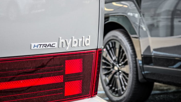 Detail zadní části hybridního vozu s chromovaným nápisem hybrid vedle koncového světla.
