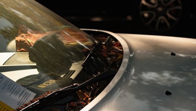Detailní pohled na čelní sklo automobilu s prostorem pro kameru asistenčních systémů ADAS, krytou plastovou maskou u zpětného zrcátka.