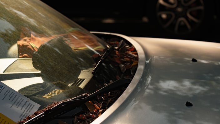 Detailní pohled na čelní sklo automobilu s prostorem pro kameru asistenčních systémů ADAS, krytou plastovou maskou u zpětného zrcátka.