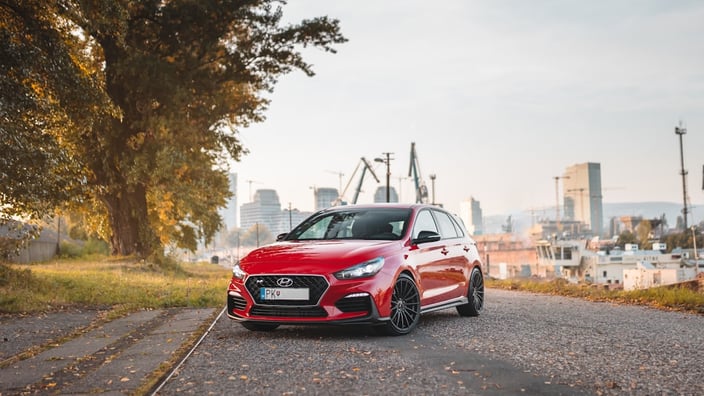 Červený Hyundai i30 pětidveřový hatchback při jízdě na silnici — jeden z nejoblíbenějších rodinných vozů na českém trhu vyžadující pravidelný servis.