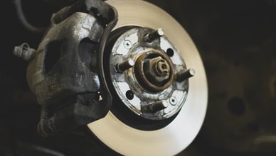 Mechanik v servisu naslouchá zvuku podvozku vozu na zvedáku během diagnostiky neobvyklého hluku.