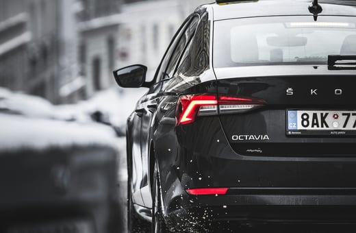 Чёрное такси Škoda Octavia в городе, представляющее наши надёжные услуги по техническому обслуживанию коммерческих и корпоративных автомобилей.