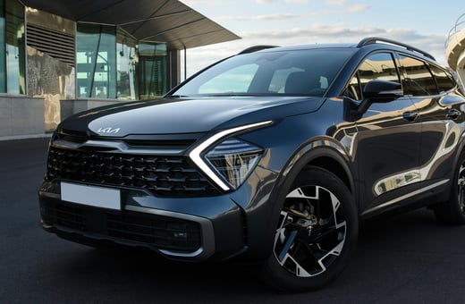 Современный внедорожник Kia Sportage, припаркованный у современного здания, олицетворяет качество и стиль, которые мы обслуживаем ежедневно.