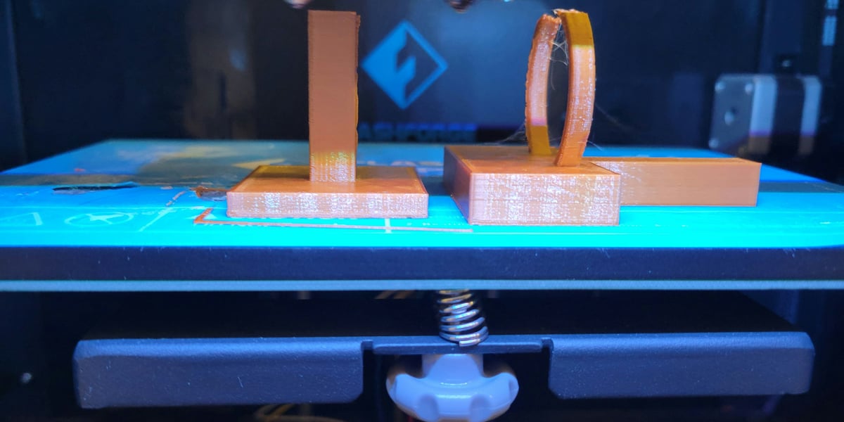 Detailní záběr na 3D tištěný plastový díl, který nahrazuje originální rozbitou součástku, ležící vedle šroubováku a dalších nástrojů.