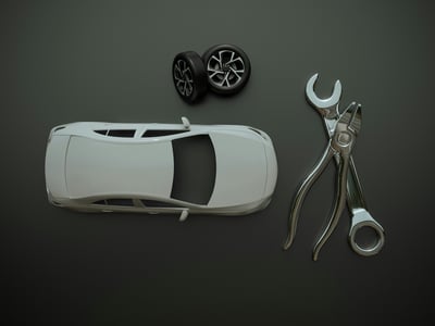 Přehledný pohled shora na 3D model bílého automobilu s dvojicí kol a velkým klíčem s kleštěmi na tmavě šedém pozadí. Předměty ilustrují zakázkovou výrobu automobilových dílů a prototypů pomocí 3D tisku.