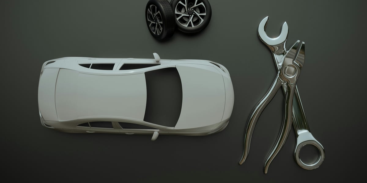 3D tištěné díly pro automobilový průmysl, včetně krytek a prototypů, ležící vedle klíče.