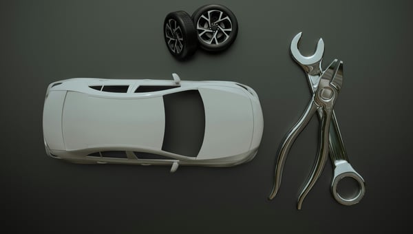 Přehledný pohled shora na 3D model bílého automobilu s dvojicí kol a velkým klíčem s kleštěmi na tmavě šedém pozadí. Předměty ilustrují zakázkovou výrobu automobilových dílů a prototypů pomocí 3D tisku.