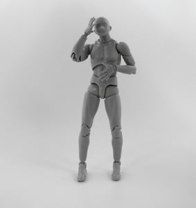 Plastový kloubový model lidské postavy v šedé barvě, který je v gestu, jako by si sahal na hlavu. Předmět je typický pro stop-motion animaci a ilustruje možnosti 3D tisku pro vytváření rekvizit a figurek.