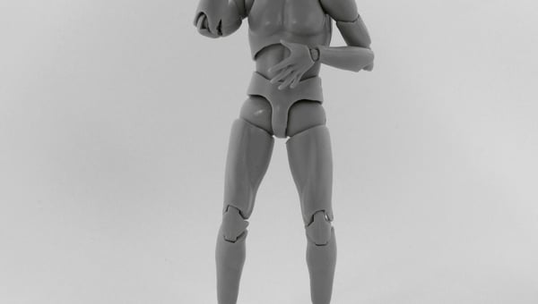 Plastový kloubový model lidské postavy v šedé barvě, který je v gestu, jako by si sahal na hlavu. Předmět je typický pro stop-motion animaci a ilustruje možnosti 3D tisku pro vytváření rekvizit a figurek.