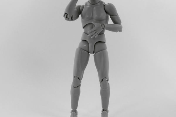 Plastový kloubový model lidské postavy v šedé barvě, který je v gestu, jako by si sahal na hlavu. Předmět je typický pro stop-motion animaci a ilustruje možnosti 3D tisku pro vytváření rekvizit a figurek.