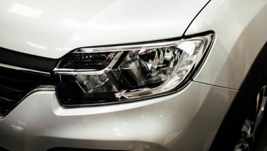 Detailní záběr na čistý a vyleštěný přední světlomet bílého moderního automobilu.