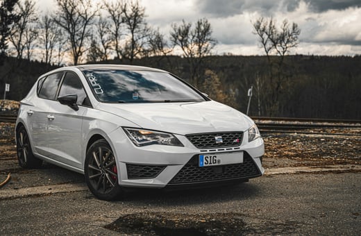 Высокопроизводительный белый хэтчбек SEAT León Cupra, демонстрирующий нашу специализацию на спортивных и энтузиастских автомобилях.
