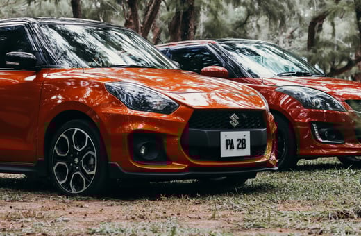 Оранжевый и красный компактные автомобили Suzuki Swift Sport, демонстрирующие наш качественный сервис для ярких и экономичных хэтчбеков.