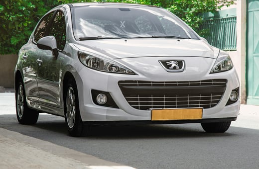 Белый компактный седан Peugeot 207, припаркованный на тихой улице — надёжный автомобиль, для которого мы с гордостью предлагаем полный комплекс услуг.