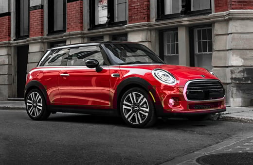 Культовый красный компактный автомобиль Mini Cooper на городской улице — популярная модель, для которой мы предоставляем экспертные специализированные услуги.