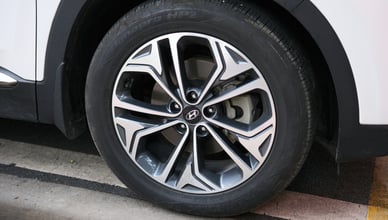 Переднее колесо белого автомобиля с современным дизайном литых дисков и шиной.