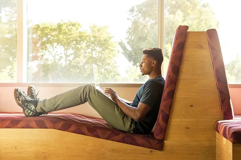 a guy sitting on a couch working remotely on his laptop