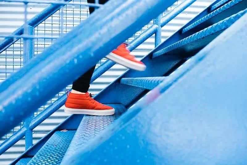 a person with orange shoes climbing blue stairs