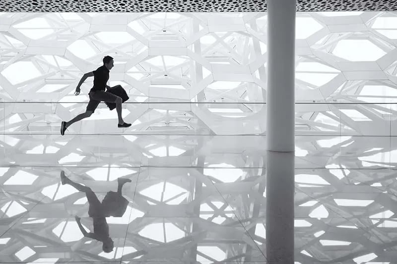 silhouette of a man running with a briefcase through a glass floor