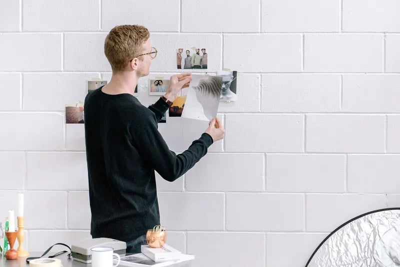 a guy hanging posters of happy customers on a white wall