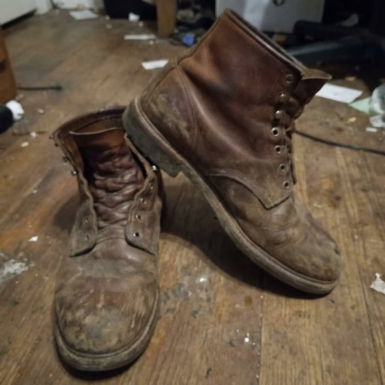 Create a close-up and clean macro shot focusing on the brand new boots’s material, finish, and texture, emphasizing the fine details, subtle reflections, and exquisite surface quality, with a dark, minimalist background that highlights the product's luxurious and sophisticated feel, capturing the way light plays across the smooth, polished surface, showcasing the intricate stitching and premium leather grain.