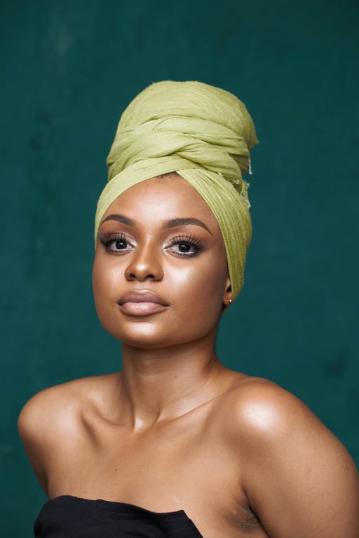 A woman in a green headwrap posing against a teal backdrop.