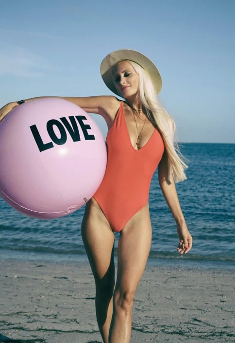 a portrait of a person edited to wear a different bathing suit style, focusing on clean swimsuit lines, accurate fabric-to-skin transitions, preserved body proportions, relaxed pose, and simple background