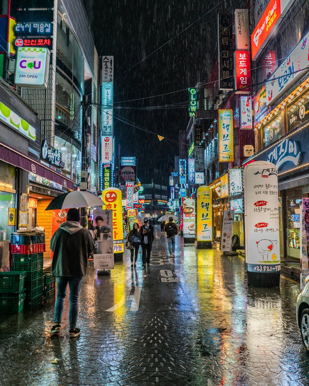 a winter transformation that adds snowfall adapted to an urban setting, with snow interacting with buildings, streets, and lights, including subtle accumulation on surfaces and realistic atmospheric depth