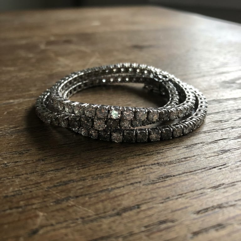 Refine the necklace into an artistic studio showcase with soft, atmospheric lighting, gentle shadows, and a subtly textured, abstract background, emphasizing the product's form and intricate textures.