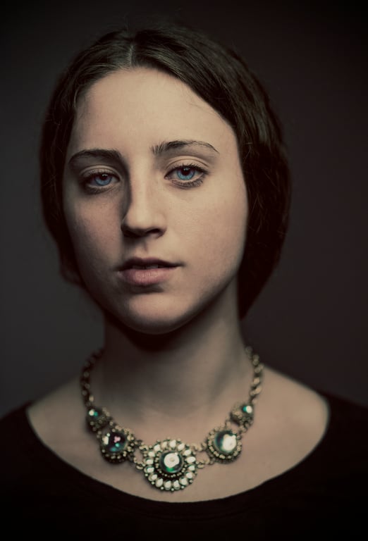 A dim, moody studio portrait with vintage lighting and minimal styling.